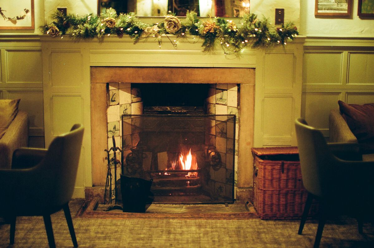 A fireplace dressed with greenery, two armchairs pulled up to it